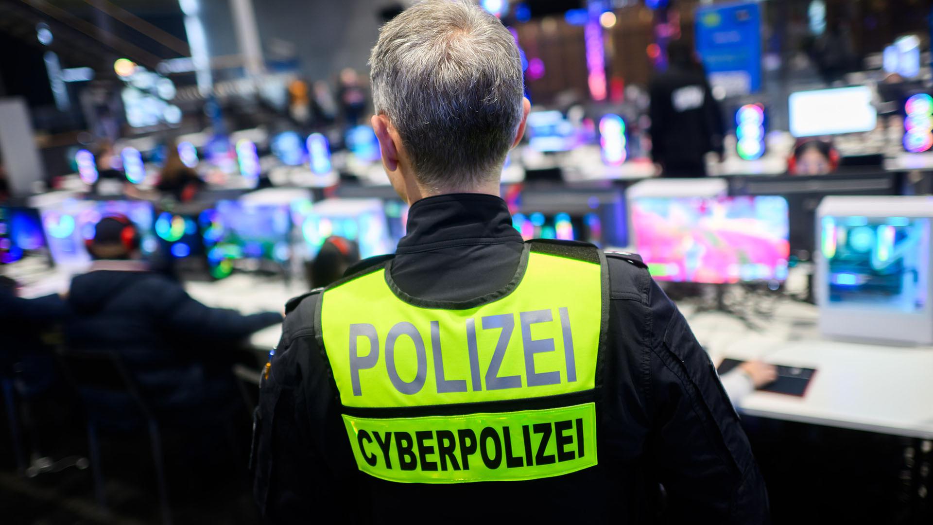Ein Polizist steht mit einer Weste mit Aufschrift Cyberpolizei