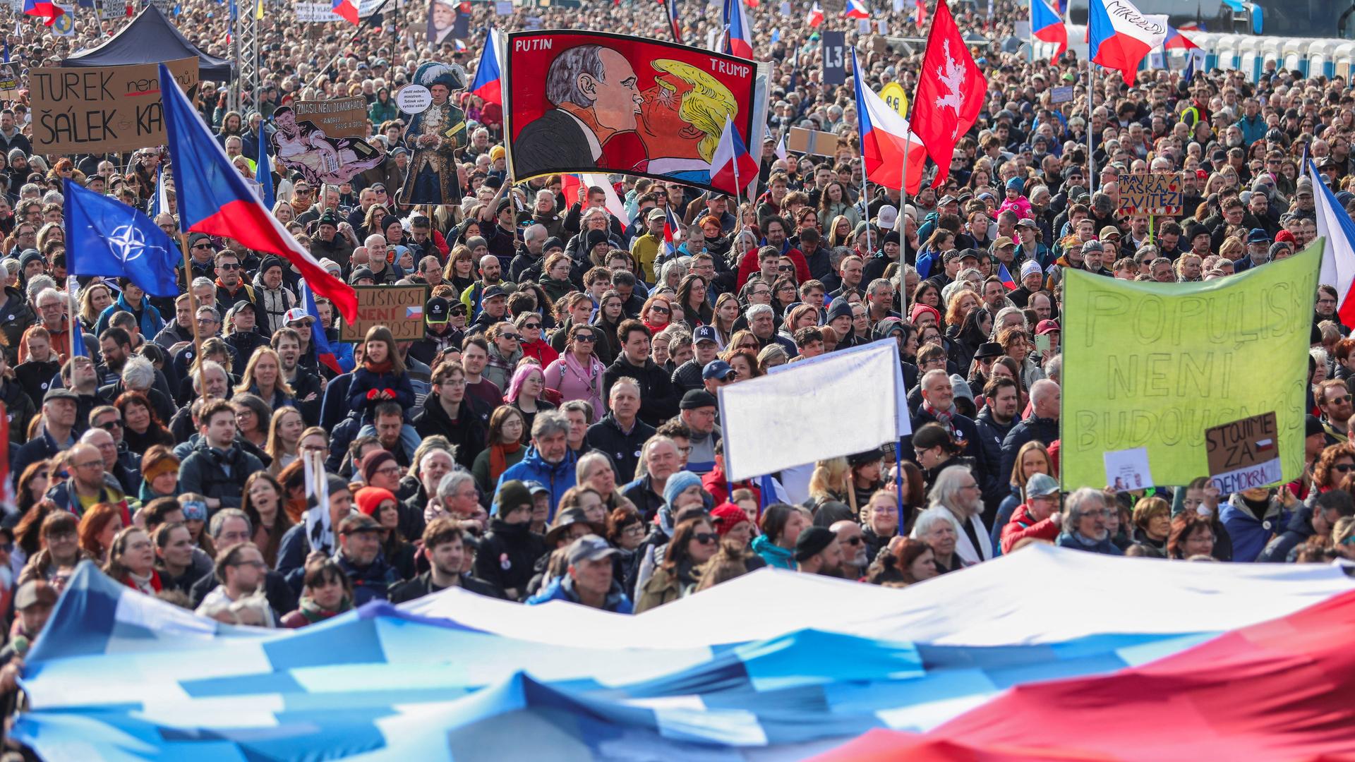 Teilnehmer einer Demonstration in Prag halten Schilder und tschechische Fahnen in die Luft. | REUTERS