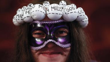 Eine Frau mit imitierten Lotteriekugeln auf dem Kopf wartet in Madrid (Spanien) auf den Beginn der Auslosung von "El Gordo"