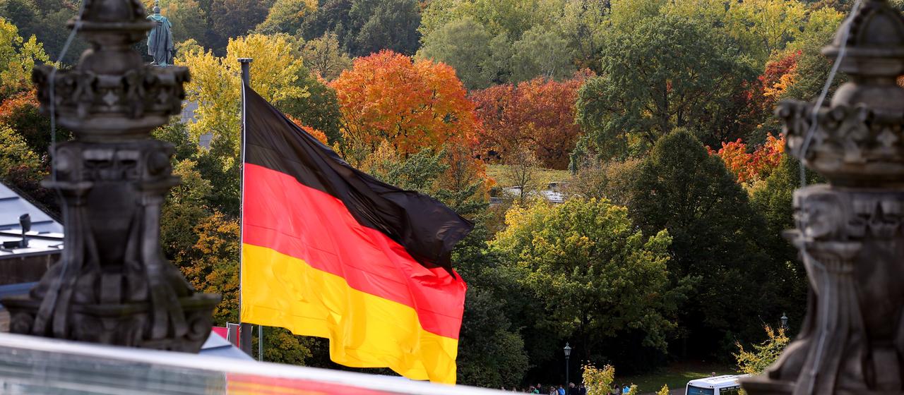 Eine Deutschland-Fahne weht über Bäumen