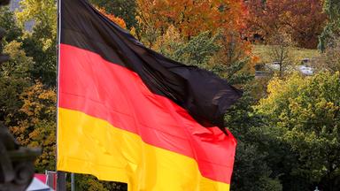 Eine Deutschland-Fahne weht über Bäumen