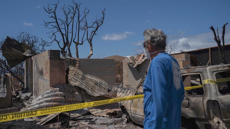 Ein Mann in Schutzkleidung blickt auf die Ruinen eines Wohnhauses.
