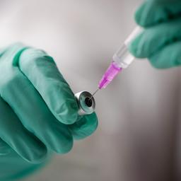 Mitarbeiterin zieht mit einer Spritze aus einem Fläschchen eine Dosis eines Corona-Impfstoffs