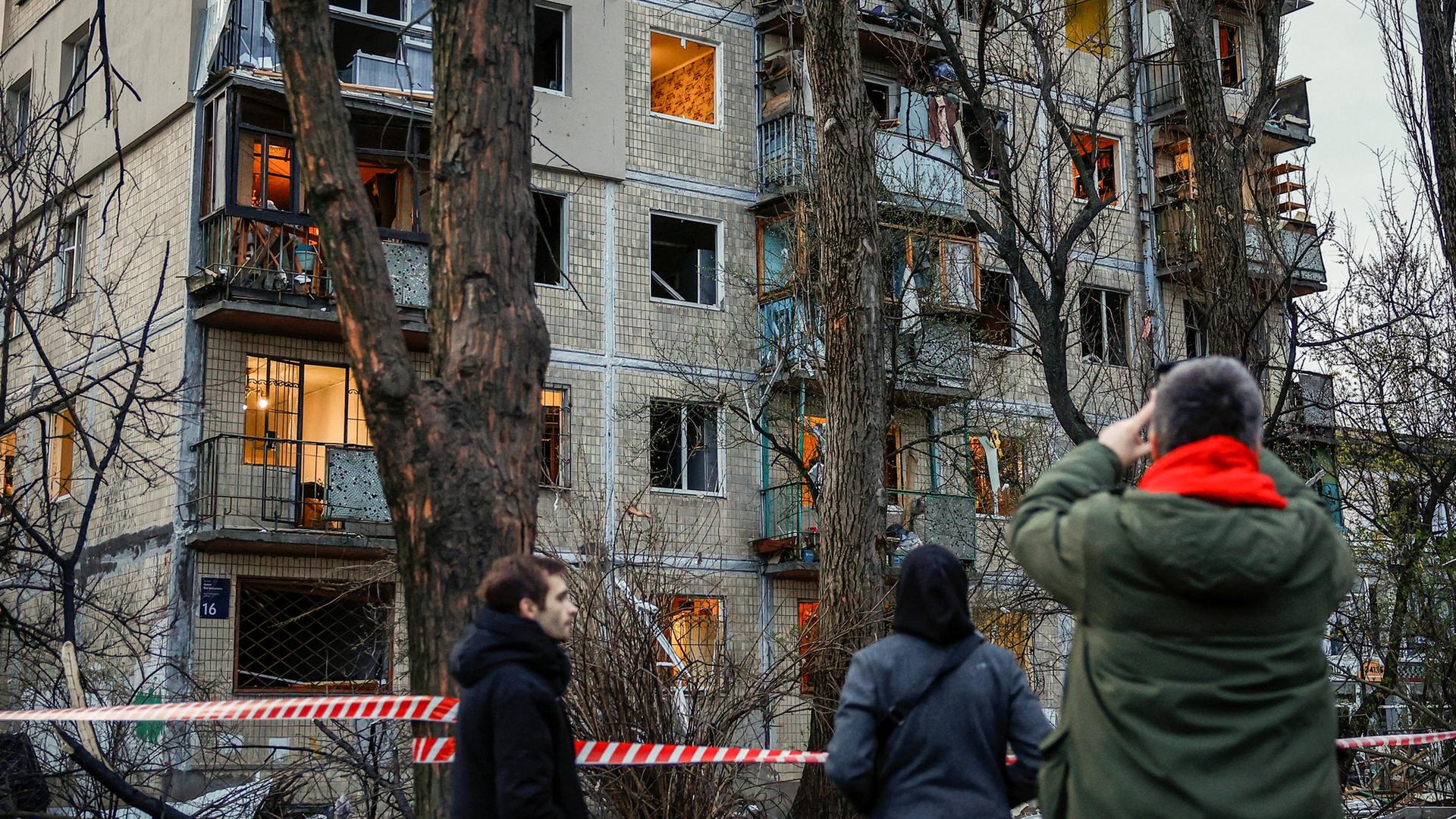 Anwohner schauen auf ein getroffenes Wohnhaus in der ukrainischen Hauptstadt Kiew | REUTERS