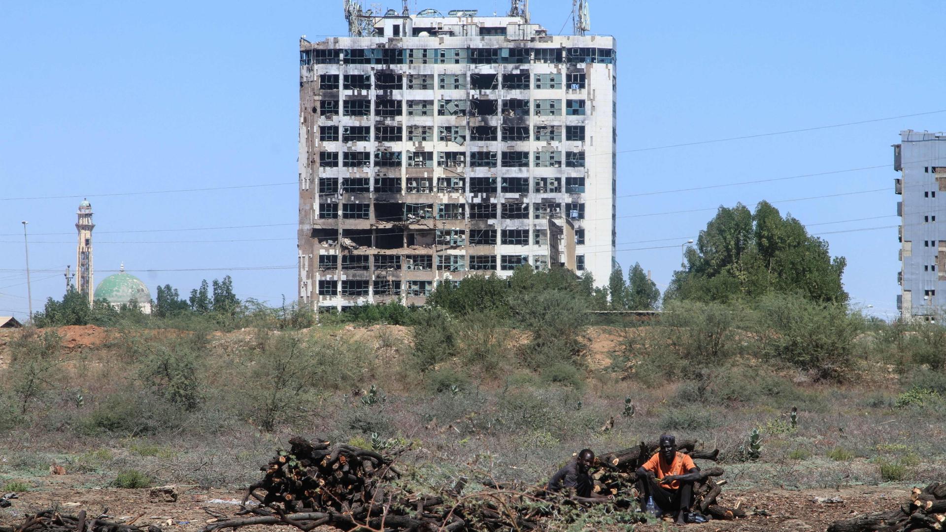 Ein Mann sitzt vor einem zerstörten Hochhaus. | AFP