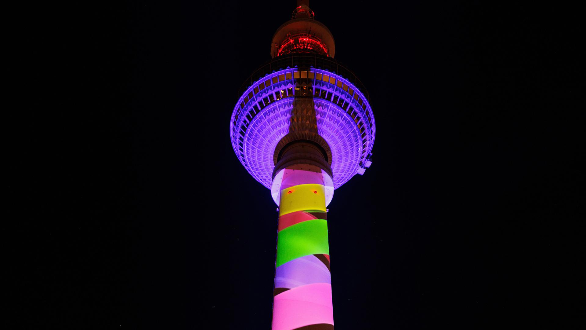 Der Berliner Fernsehturm wird in mehreren Farben angestrahlt. | dpa