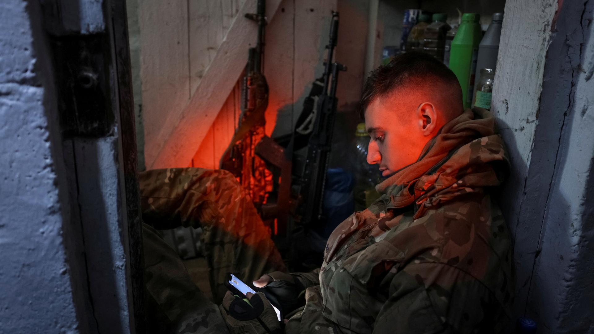 Ein ukrainischer Soldat schaut auf sein Handy in einem Lager an der Front. | via REUTERS