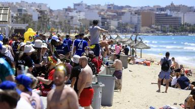 Menschen feiern und sonnen sich vor dem Pfingstwochenende am Strand von Arenal auf Mallorca.