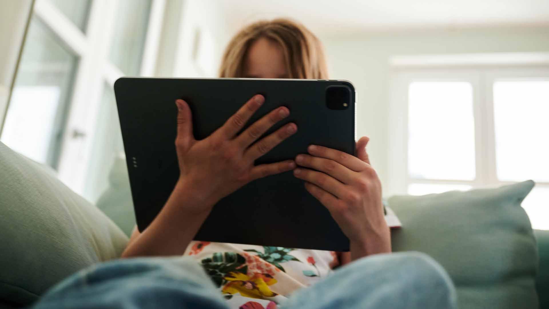 Eine Jugendliche sitzt mit einem Tablet auf einem Sofa. | picture alliance/dpa