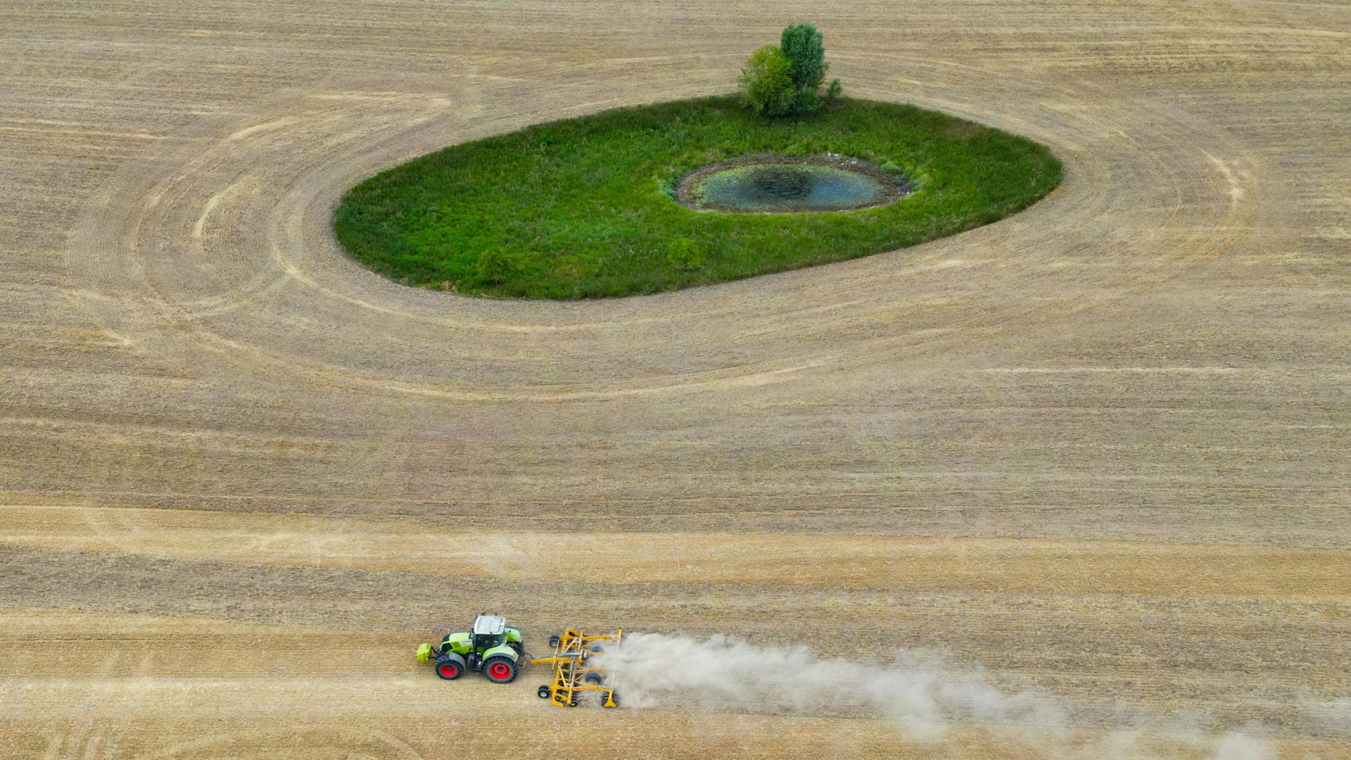 Ein Landwirt fährt mit einer Scheibenegge über ein abgeerntetes Getreidefeld im östlichen Brandenburg und wirbelt dabei viel Staub auf | dpa