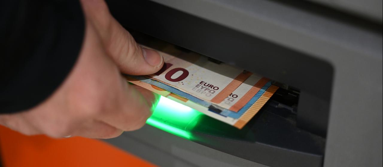 Eine Person hebt Geld an einem Geldautomaten ab