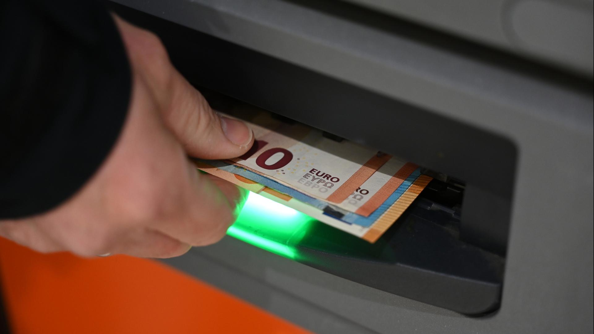 Eine Person hebt Geld an einem Geldautomaten ab | dpa