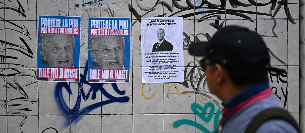 Ein Mann sieht sich aufgeklebte Plakat gegen Jose Antonio Kast an.