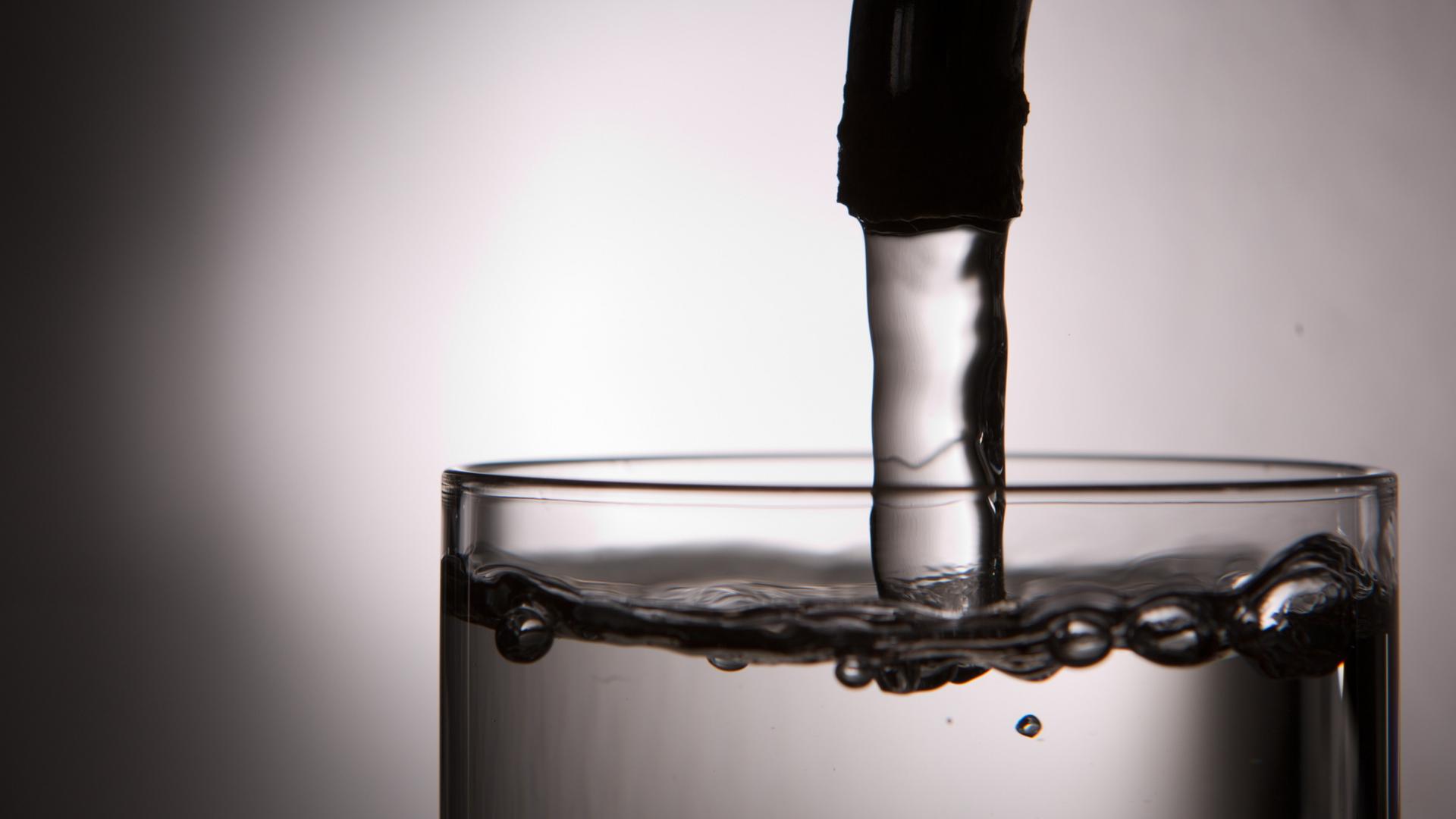Wasser fließt aus einem Hahn in ein Glas. | dpa