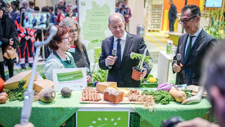 Bundeskanzler Olaf Scholz (M, SPD) schaut sich auf der Grünen Woche neben Cem Özdemir (Bündnis 90/Die Grünen), Bundesminister für Ernährung und Landwirtschaft, den "ewigen Kohl· an. 