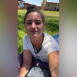 Die Deutsche Carolina Wilga macht ein Selfie, während sie auf einer Wiese liegt.