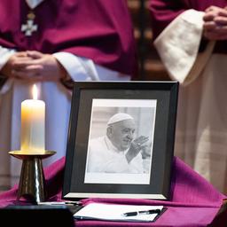 Ein Foto von Papst Franziskus steht neben einer brennenden Kerze.