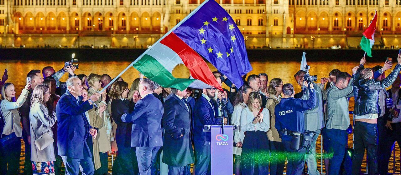 Fahnen werden geschwenkt, davor steht ein Rednerpult