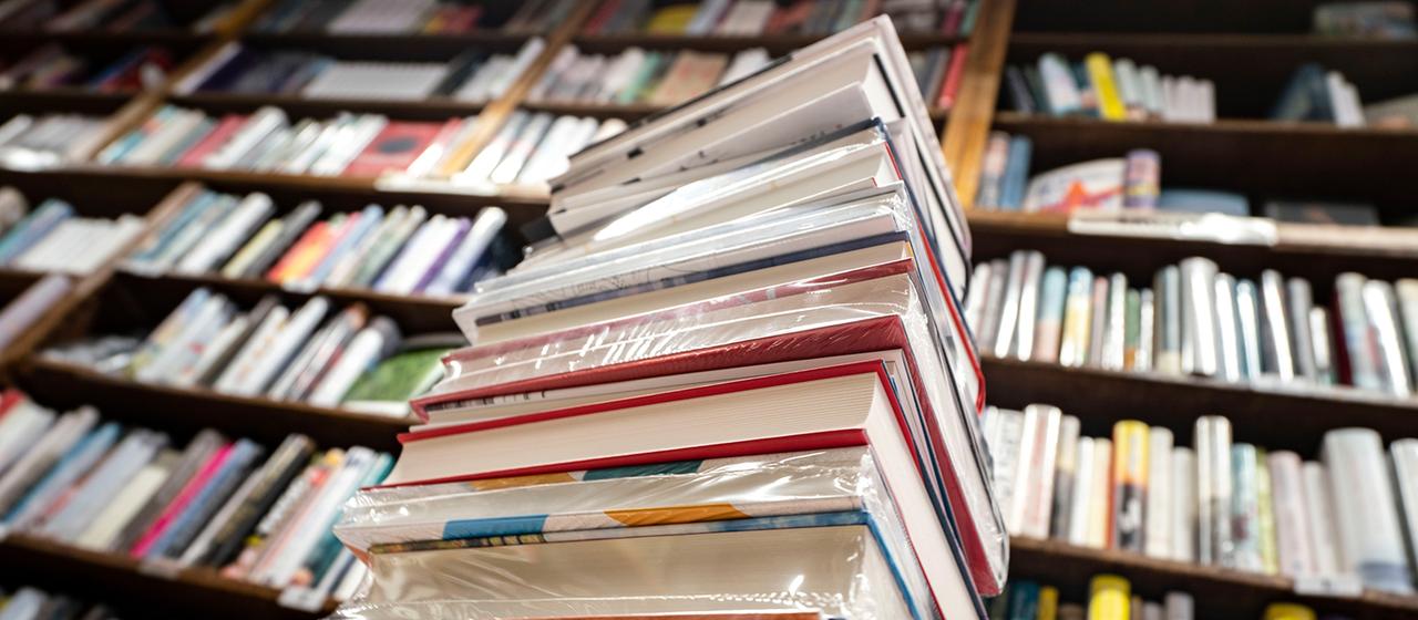 Ein Stapel neuer Bücher liegt auf einem Verkaufstisch in einer Buchhandlung.