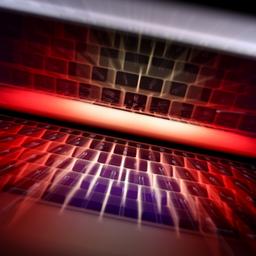 Die Tastatur eines Laptops spiegelt sich in dessen Bildschirm (Aufnahme mit Zoomeffekt). 
