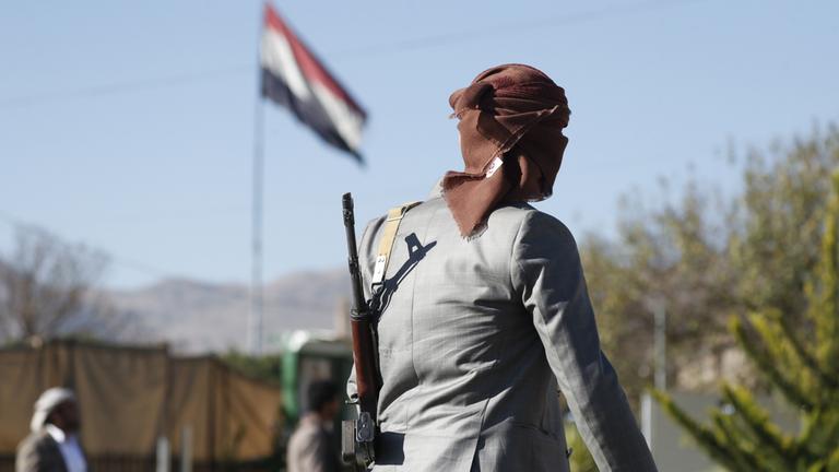 Ein bewaffneter Huthi-Kämpfer geht an einer jemenitischen Fahne vorbei in Sanaa, Jemen.