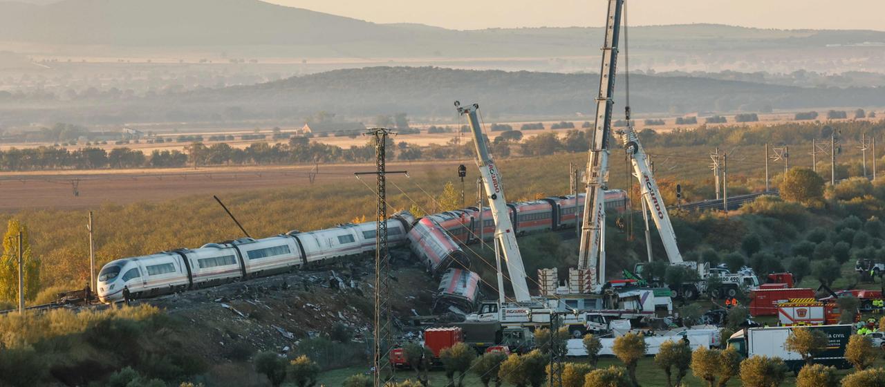 Kräne stehen neben den Waggon-Trümmern an der Unglücksstelle der Zugkollision in Spanien