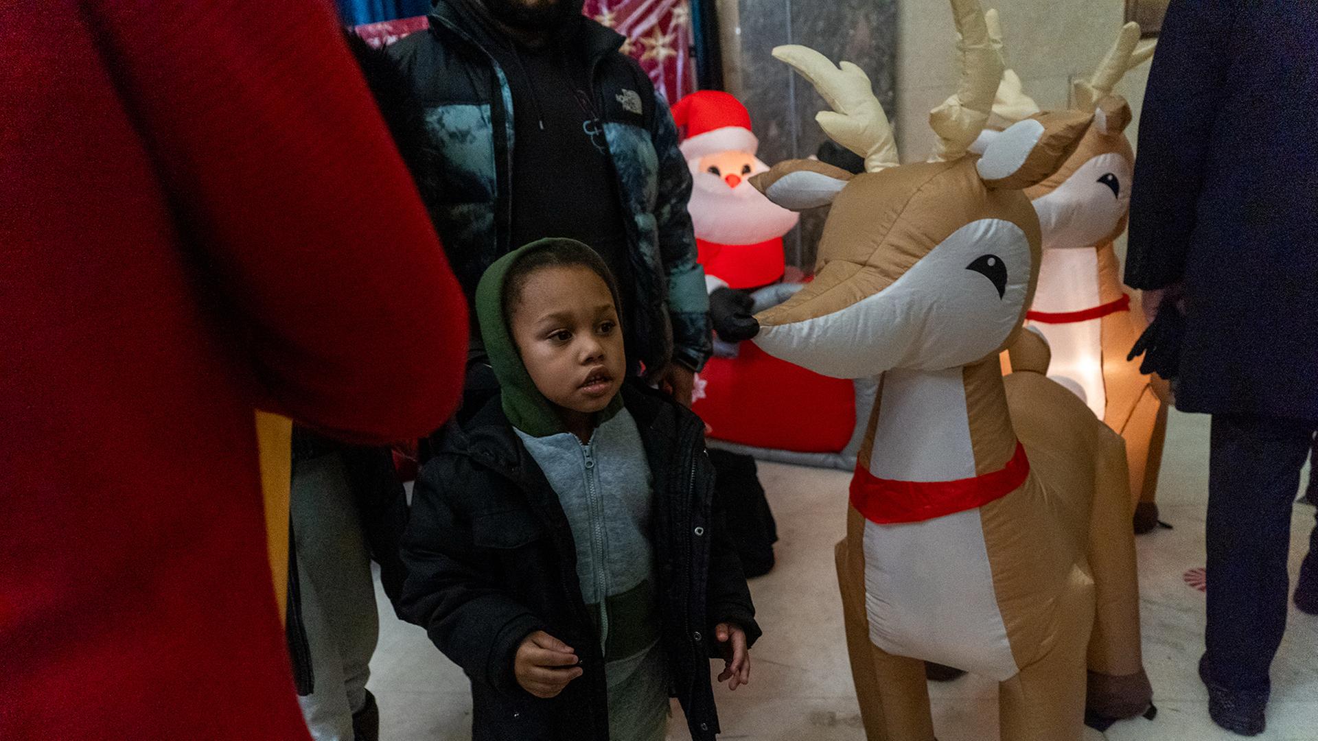 Ein Kind steht neben Weihnachtsdekoration im Stadtteil Bronx in New York. | EPA