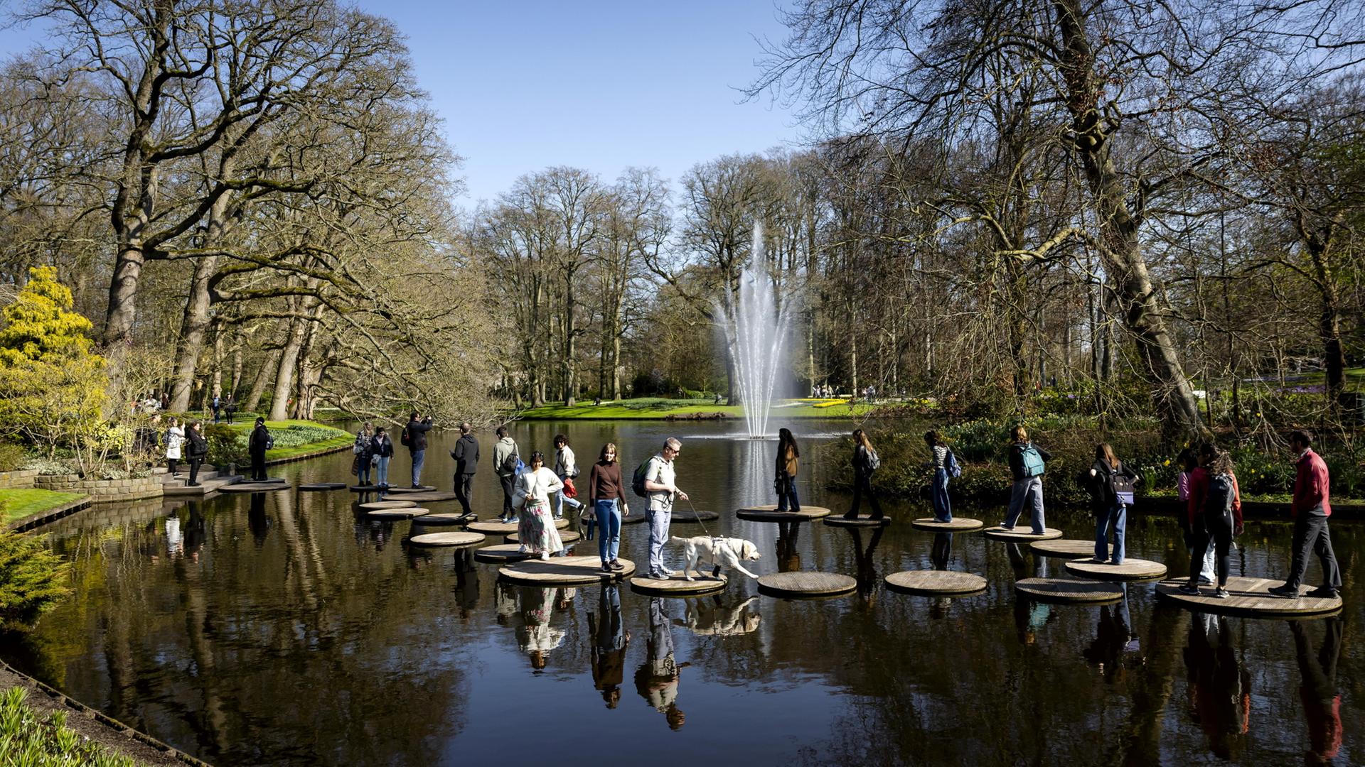 Besucher im Keukenhof-Blumengarten gehen Ã¼ber Steinplatten in einem See. | EPA