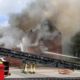 Ein Wohnaus steht im Vollbrand und Feuerwehrleute löschen den Brand