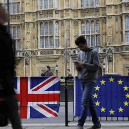 Passanten laufen an der britischen und europäischen Flagge vor dem britischen Parlament vorbei.