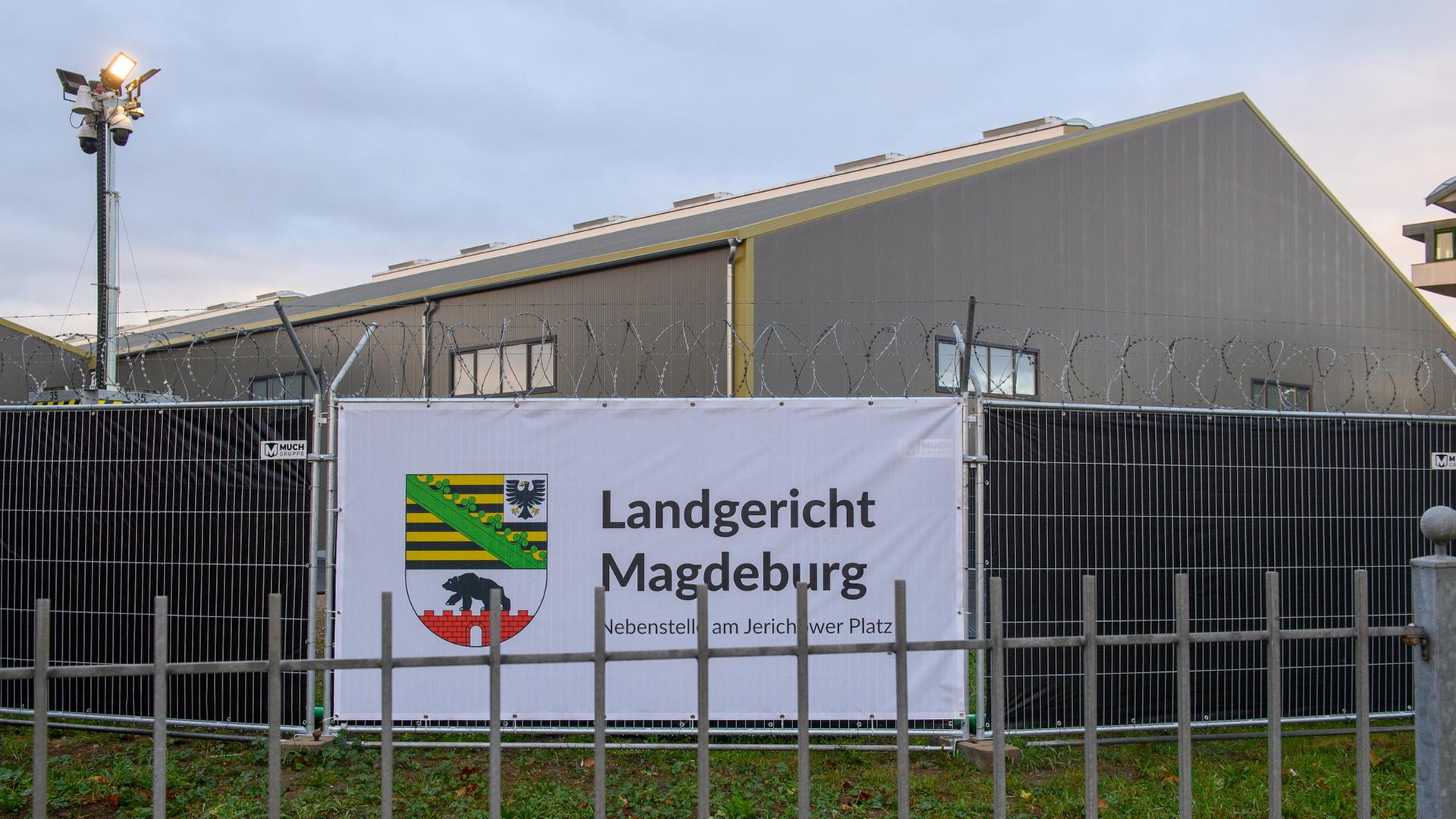 Gebäude hinter einem Zaun mit Banner, auf dem 