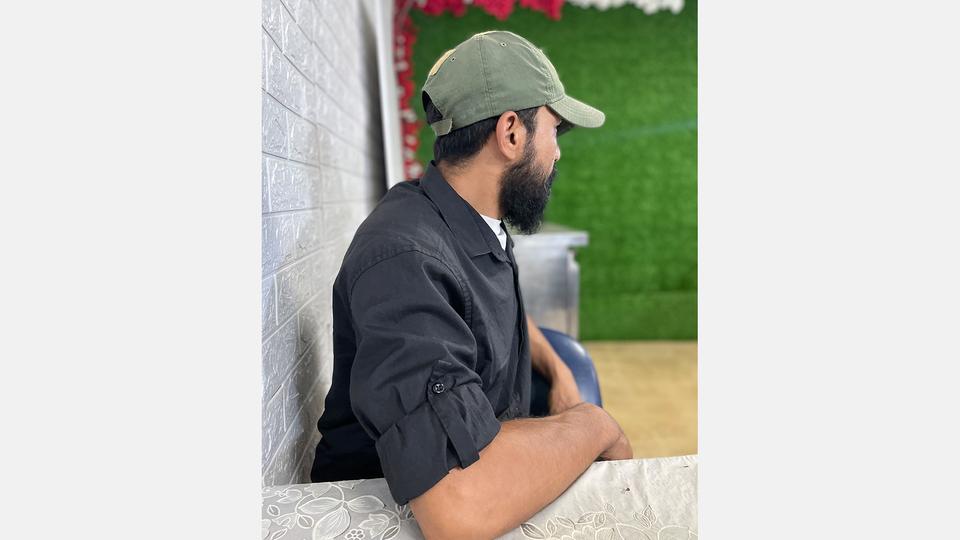 Ein Hisbollah-Kämpfer der sich Ali nennt sitzt an einem Tisch und ist von der Kamera abgewandt.