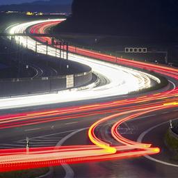 Leuchtspuren des Autoverkehrs auf einer Autobahn in einer Langzeitbelichtung.