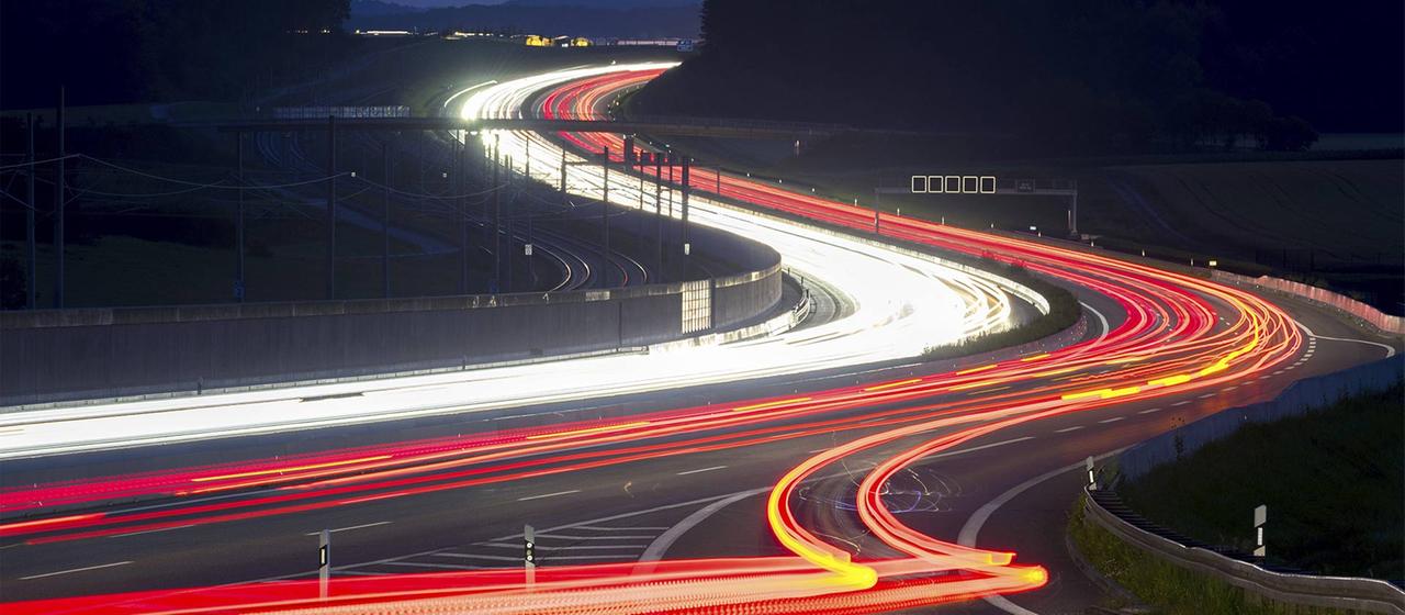 Leuchtspuren des Autoverkehrs auf einer Autobahn in einer Langzeitbelichtung.