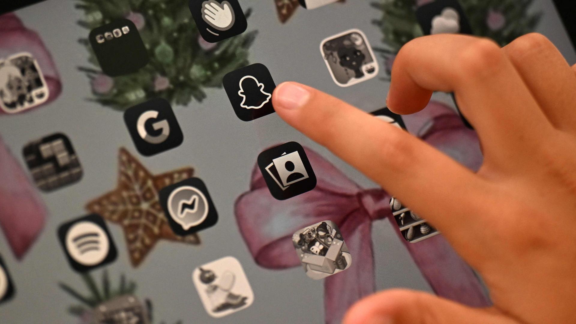 Ein Kind zeigt auf ein Snapchat-Symbol. | AFP