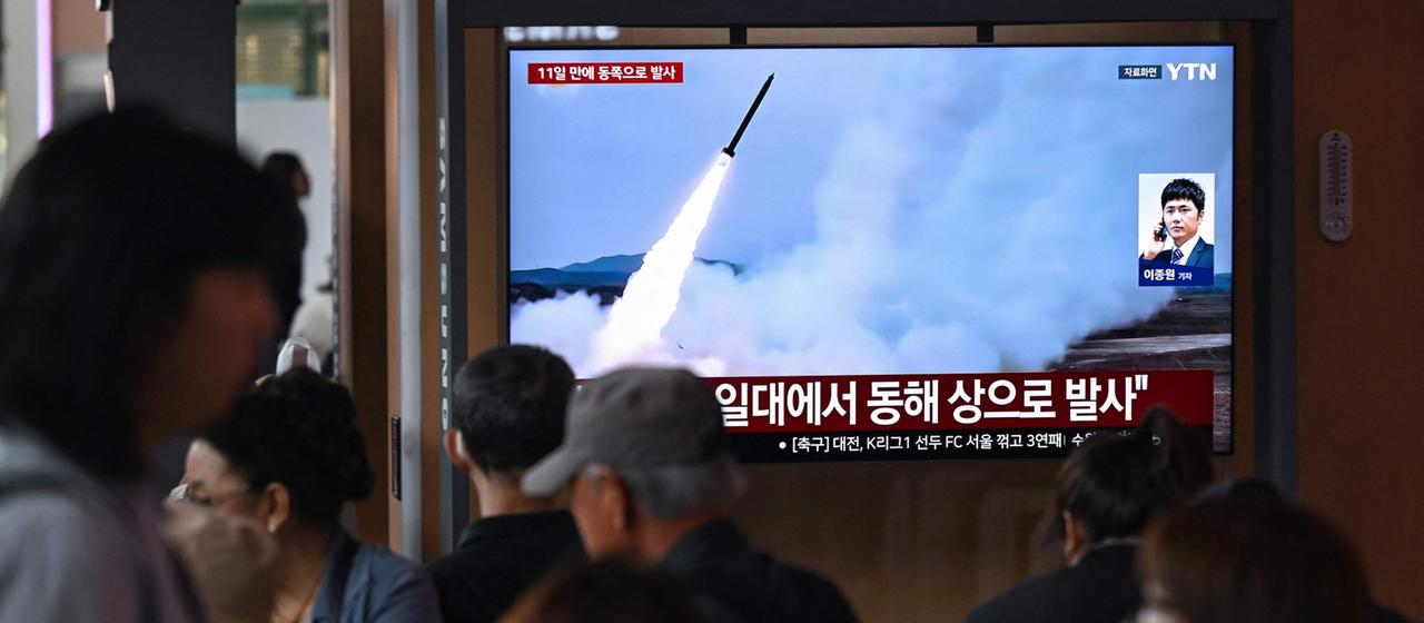 Menschen gehen in in einem Bahnhof in Seoul an einem Bildschirm vorbei, der einen nordkoreanischen Raketenstart zeigt.