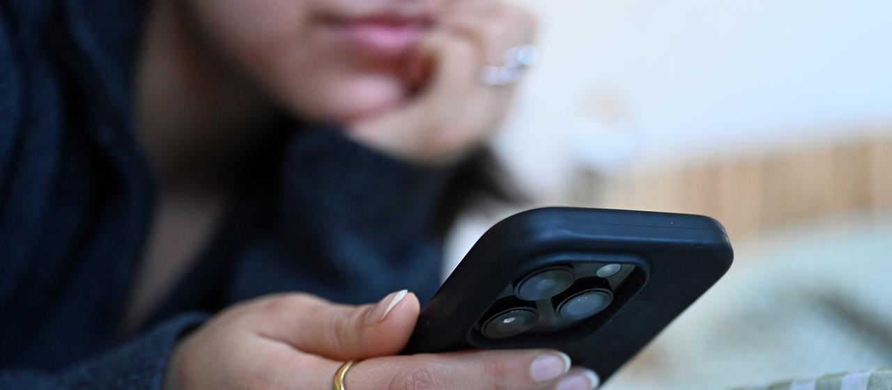 Eine junge Frau hält ein Smartphone.