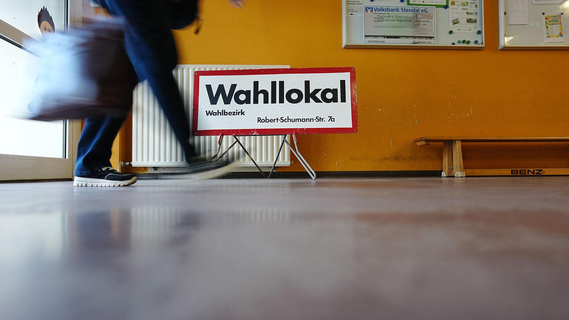  Wahlhelferin geht in einem Wahllokal in Tangermünde an dem Schild 