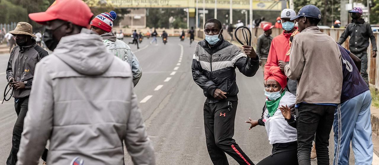 Mit Peitschen und Knüppeln bewaffnete Männer packen eine Demonstrantin in Nairobi.