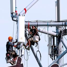 Arbieter in Klettermontur bei der Montage eines 5G Mobilfunksender