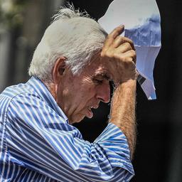 Ein Mann in Griechenland schützt seinen Kopf mit einem Papier vor der Sonne.