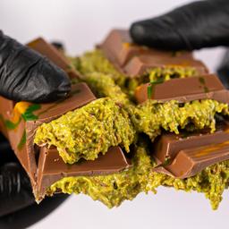 Behandschuhte Hände zerbrechen Dubai-Schokolade, aus der die Füllung quillt.