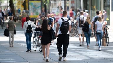 Passanten gehen auf einer  Einkaufsstraße in Dresden an den Geschäften entlang. 