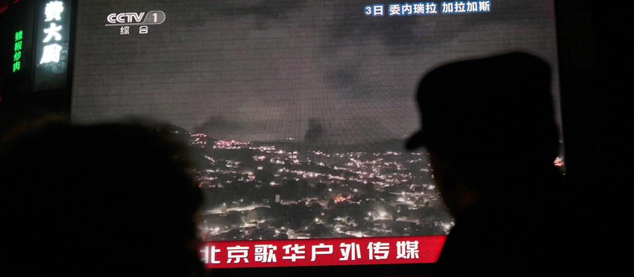 Menschen beobachten auf einem TV in Peking den US-Angriff auf Venezuela