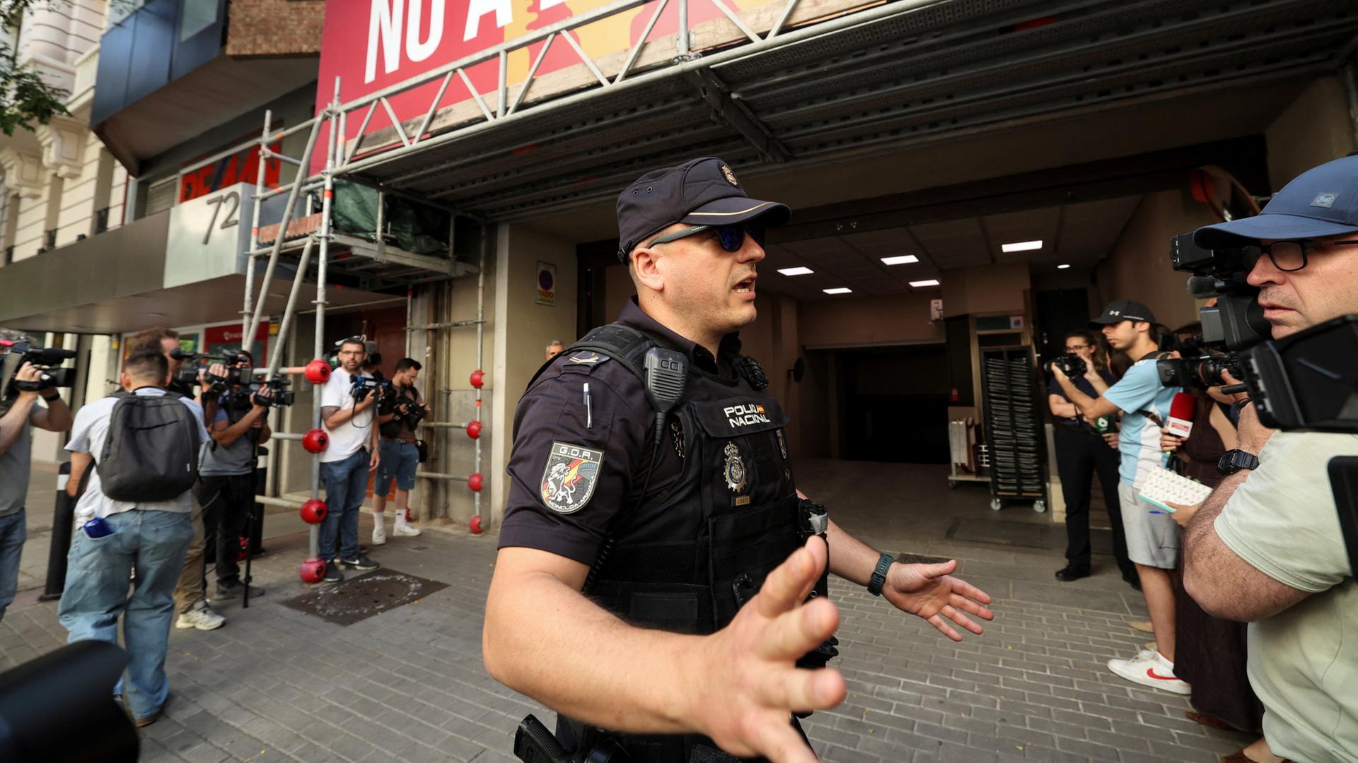 Medienvertreter sind vor dem Gebäude der PSOE  zu sehen, während die spanische Polizei den Zugang zum Hauptsitz der Sozialistischen Partei absperrt. | REUTERS