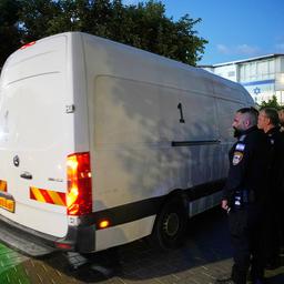 Ein Transporter fährt an Sicherheitskräften vorbei.