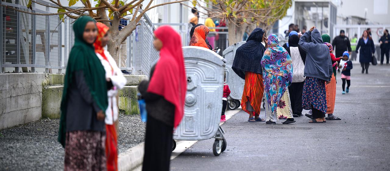 Geflüchtete stehen im Aufnahme- und Unterbringungszentrum für Asylbewerber in der Gemeinde Kofinou auf Zypern vor Wohncontainern. 