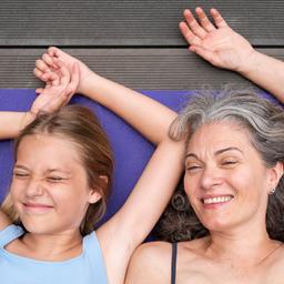 Mutter und Tochter liegen auf einer Matte.