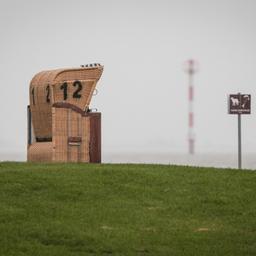 Ein leerer Strandkorb steht unter einem grauen, regnerischen Himmel am Kutterhafen von Wremen