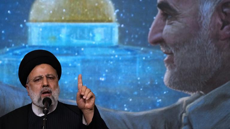 Ebrahim Raisi während einer Gedenkfeier für den verstorbenen Revolutionsgardengeneral Soleimani, der im Hintergrund auf einem Bildschirm zu sehen ist (aufgenommen am 3. Januar 2024)